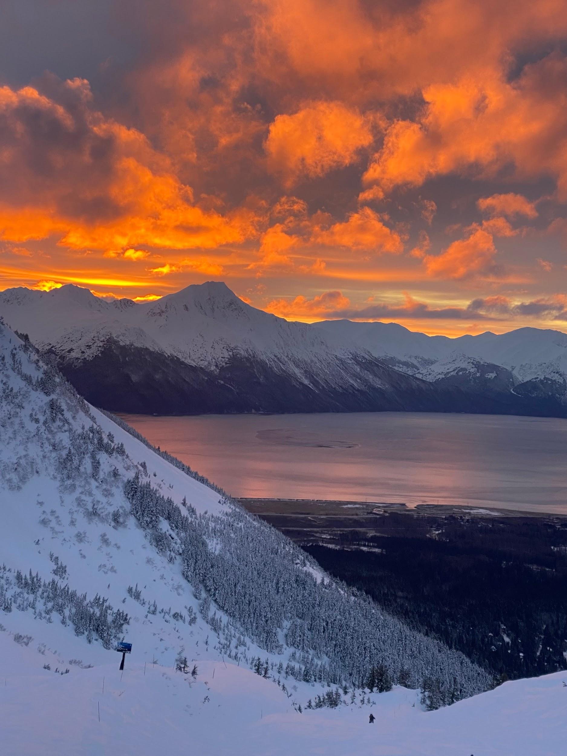 Snowy mountain peaks under a fiery sunset sky